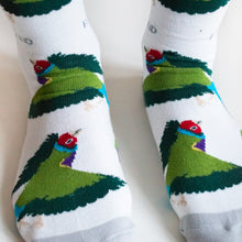 closeup of model wearing white gouldian finch bamboo socks, highlighting the green wings of the bird woven into the sock