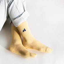 model sitting with ankles crossed wearing pastel yellow ribbed bamboo socks