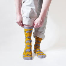 standing model pulls up yellow rhino socks by the grey cuff