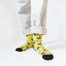 model stands with the ankles together and toes out as they wear black and yellow bee socks