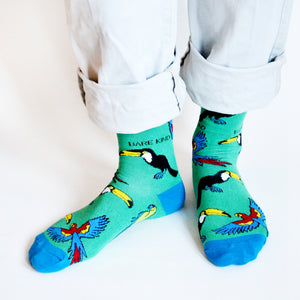 standing model wearing green and blue toucan socks