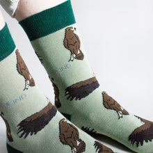 model wearing green eagle socks, side angle view closeup of ankle and woven eagle design
