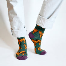 standing model wearing green tiger socks with left heel raised