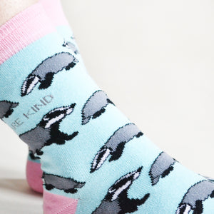 model wearing blue and pink badger socks, side angle view, closeup of the ankle and animal print woven into the bamboo socks