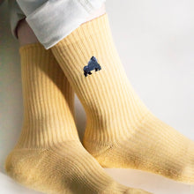 closeup of model wearing pastel yellow ribbed bamboo socks with ankles crossed