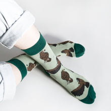 birds eye view of model wearing green eagle socks as the ankles are crossed