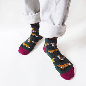 front view of standing model wearing dark green fox socks, with the left foot forward