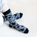sitting model with ankles crossed wearing grey and black orca bamboo socks, birds eye view