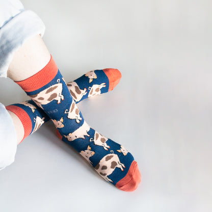 birds eye view of sitting model wearing navy blue pig bamboo socks with ankles crossed