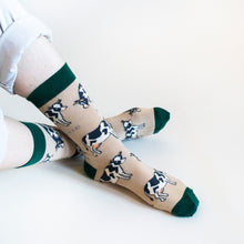 Model side angle view wearing cream and green bamboo cow socks as the ankles are crossed