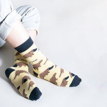 sitting model with crossed ankles wearing pastel yellow platypus socks