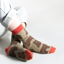 model wears brown and red bamboo bear socks as they sit with crossed ankles