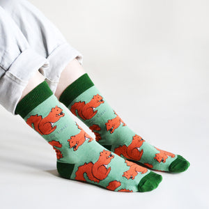 sitting model wears red squirrel bamboo socks, side angle view