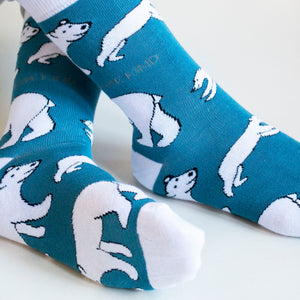 closeup of sitting model wearing blue and white polar bear bamboo socks, highlighting the woven polar bear design