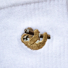 closeup of embroidered sloth motif on the cuff of white ribbed bamboo sock