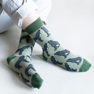 sitting model with ankles crossed wearing green wolf socks